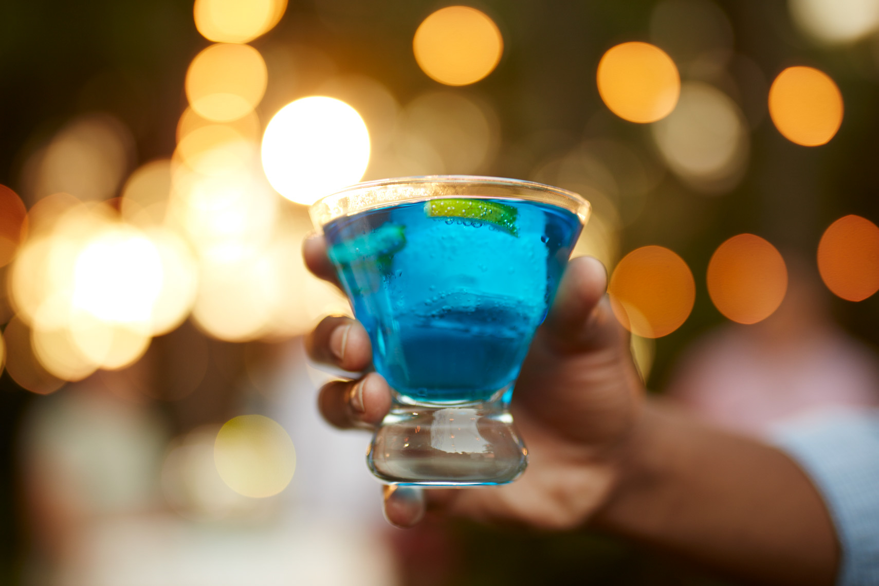 man holding glass with blue drink and slices of lime San Francisco food photographer
