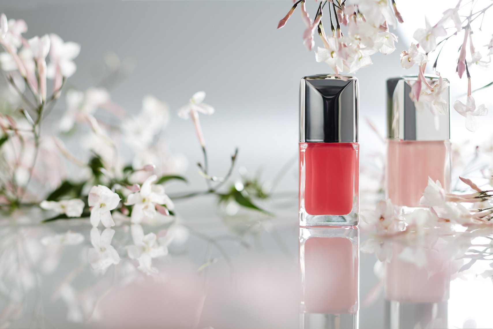 2 bottles of pink nail polish with white lilies on white marble surface San Francisco product photographer