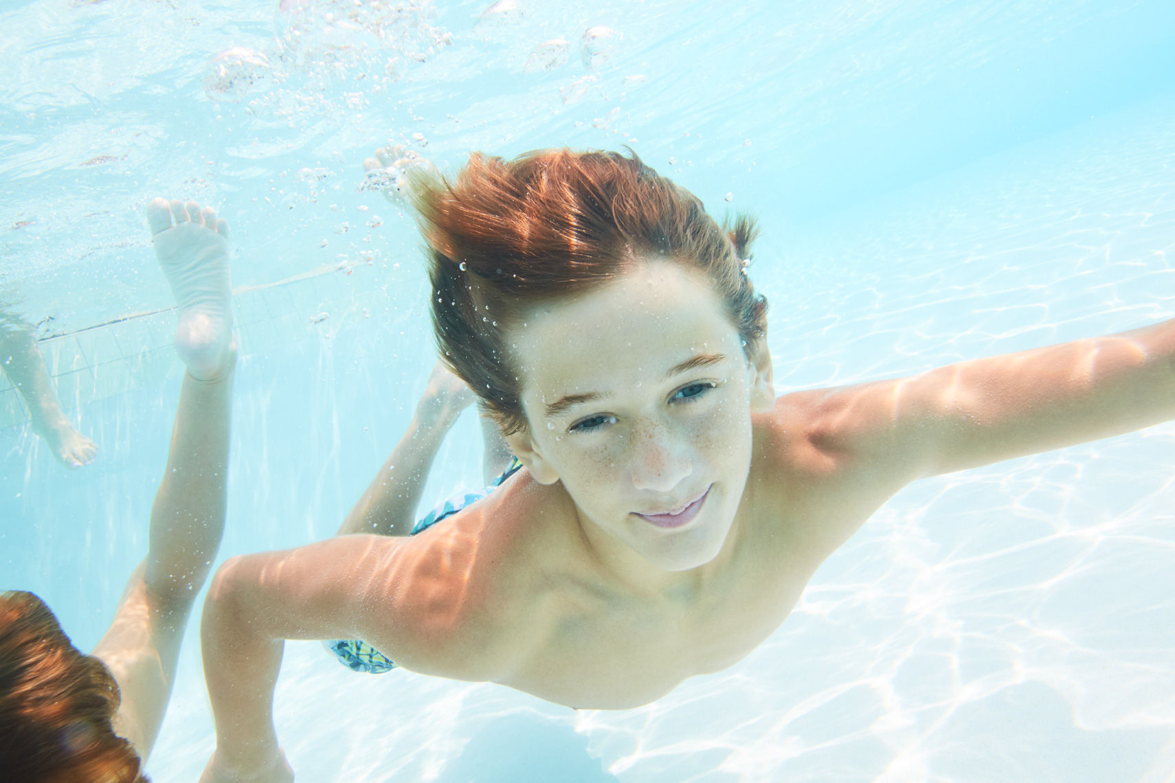 Young boy swims under water toward camera on sunny day San Francisco lifestyle photographer