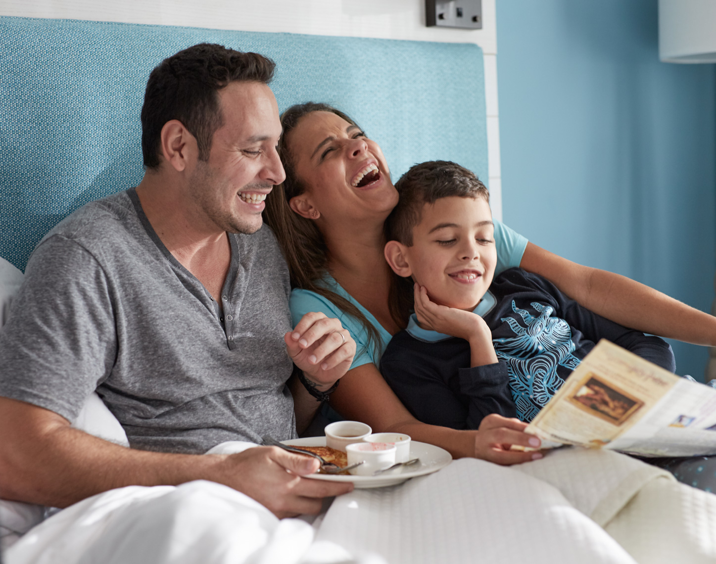 Family in hotel bed laughing and looking at a map San Francisco lifestyle photographer