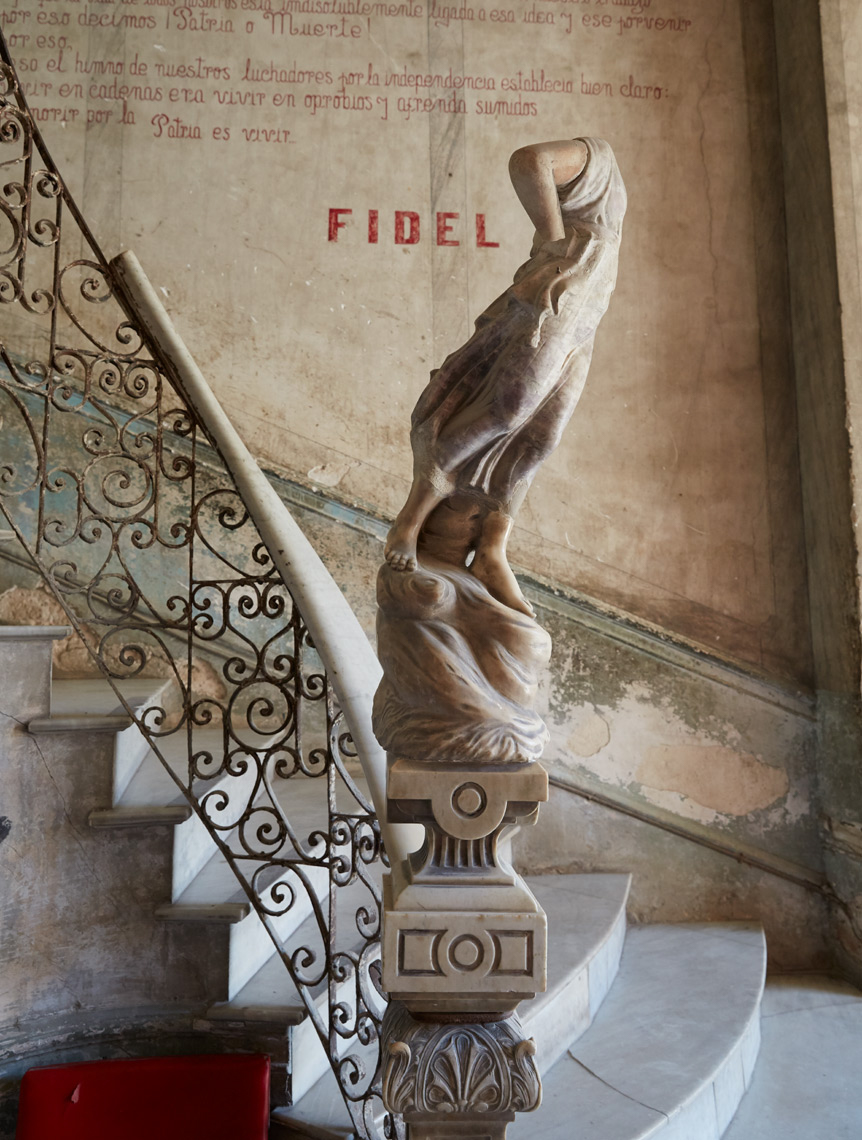 old statue on antique marble staircase with Fidel Castro quote on wall