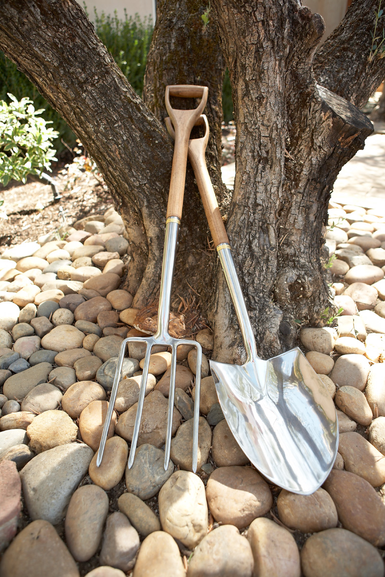 Chrome shovel and pitch fork with wooden handles leaning against tree San Francisco product photographer