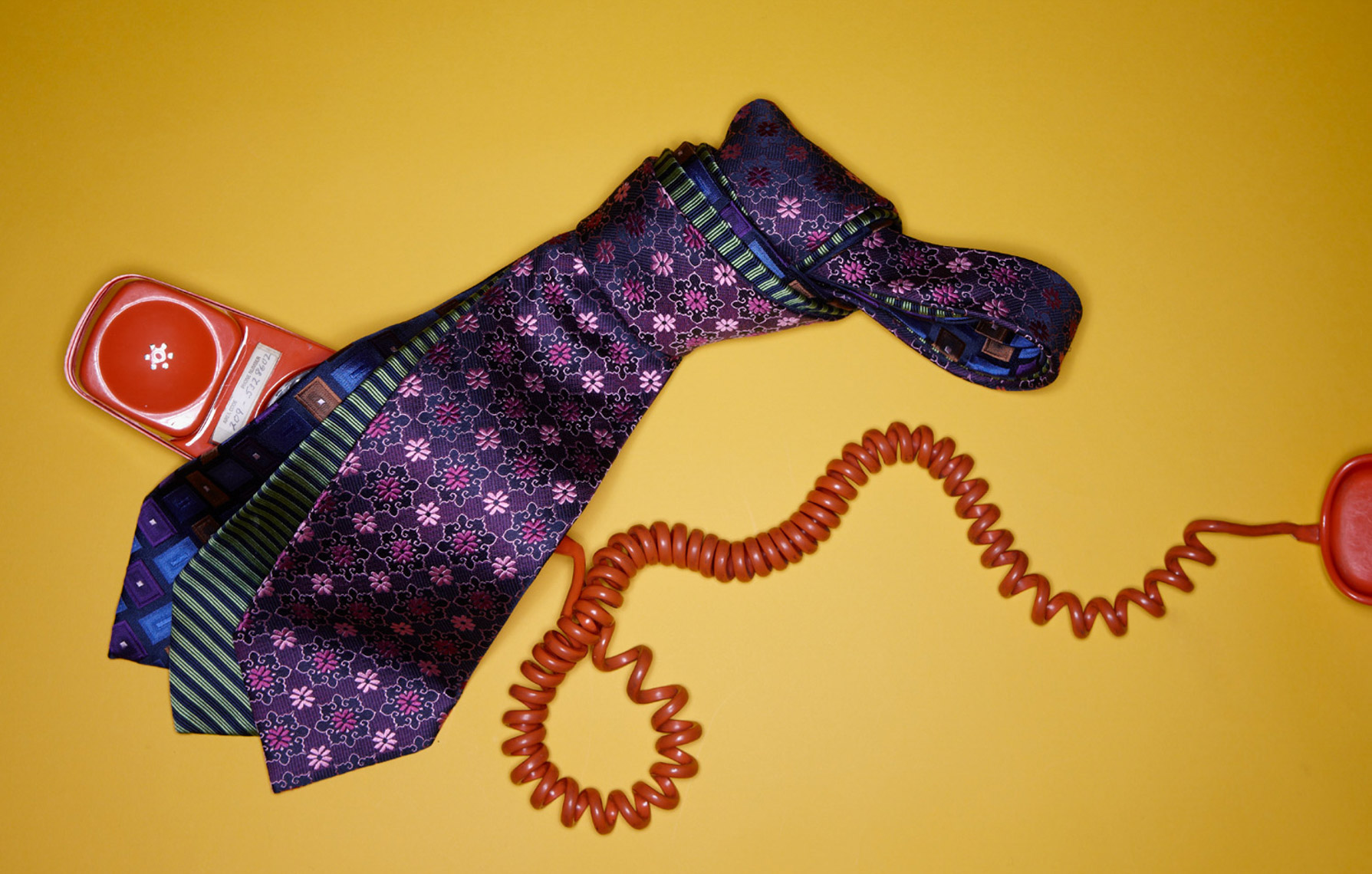 purple and green patterned ties with red telephone chord on yellow surface San Francisco product photographer